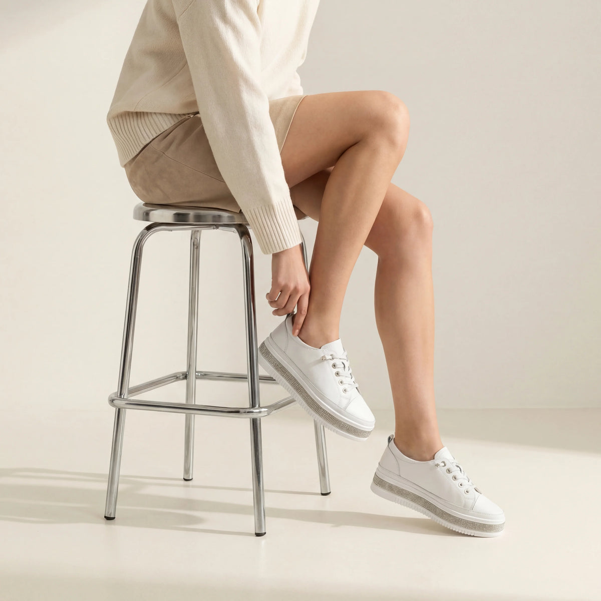 A white low-top platform sneaker with a textured, rhinestone-embellished midsole and white laces