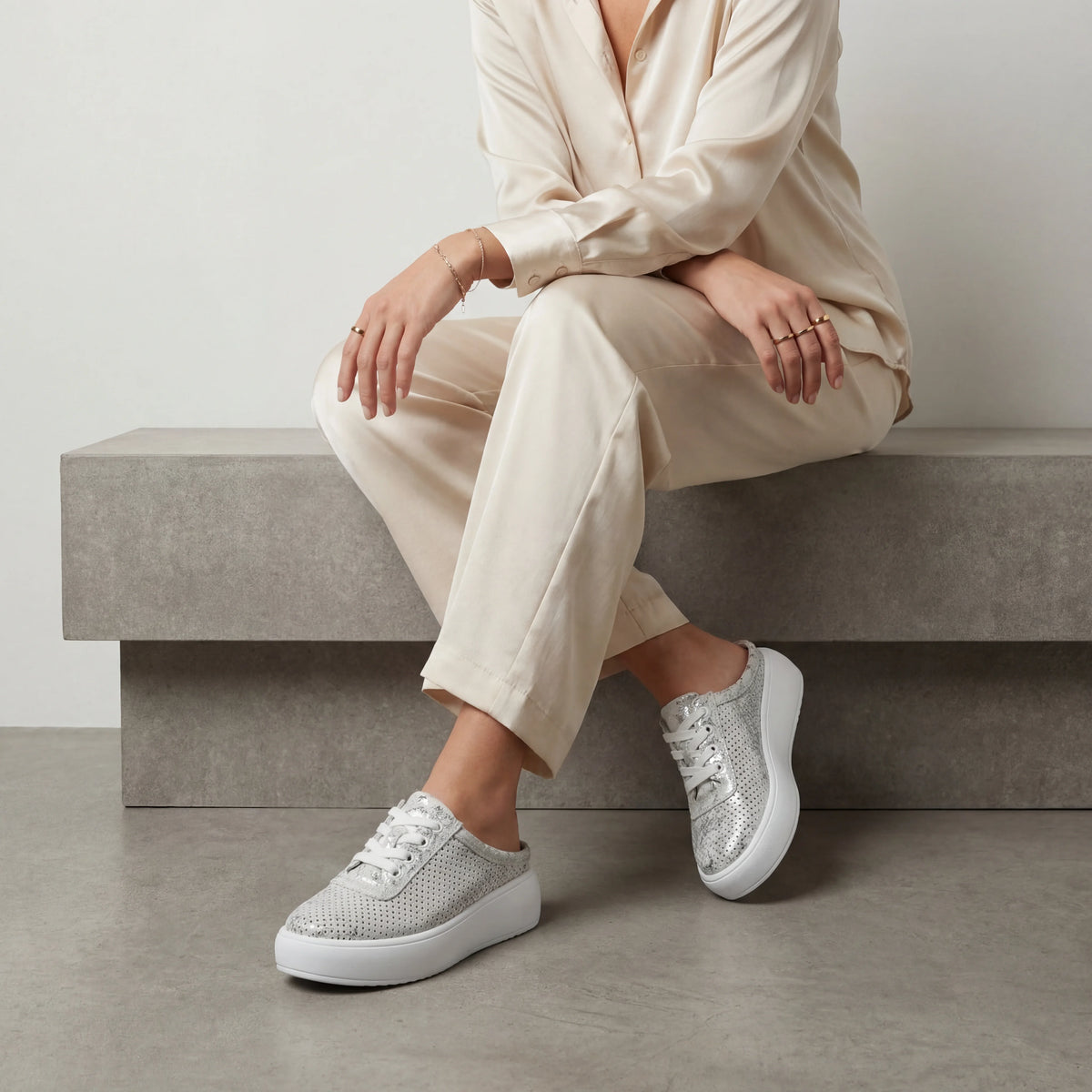 A grey and silver metallic platform mule sneaker with a perforated upper, easy slip-on design and lightweight cushioned sole for everyday wear.