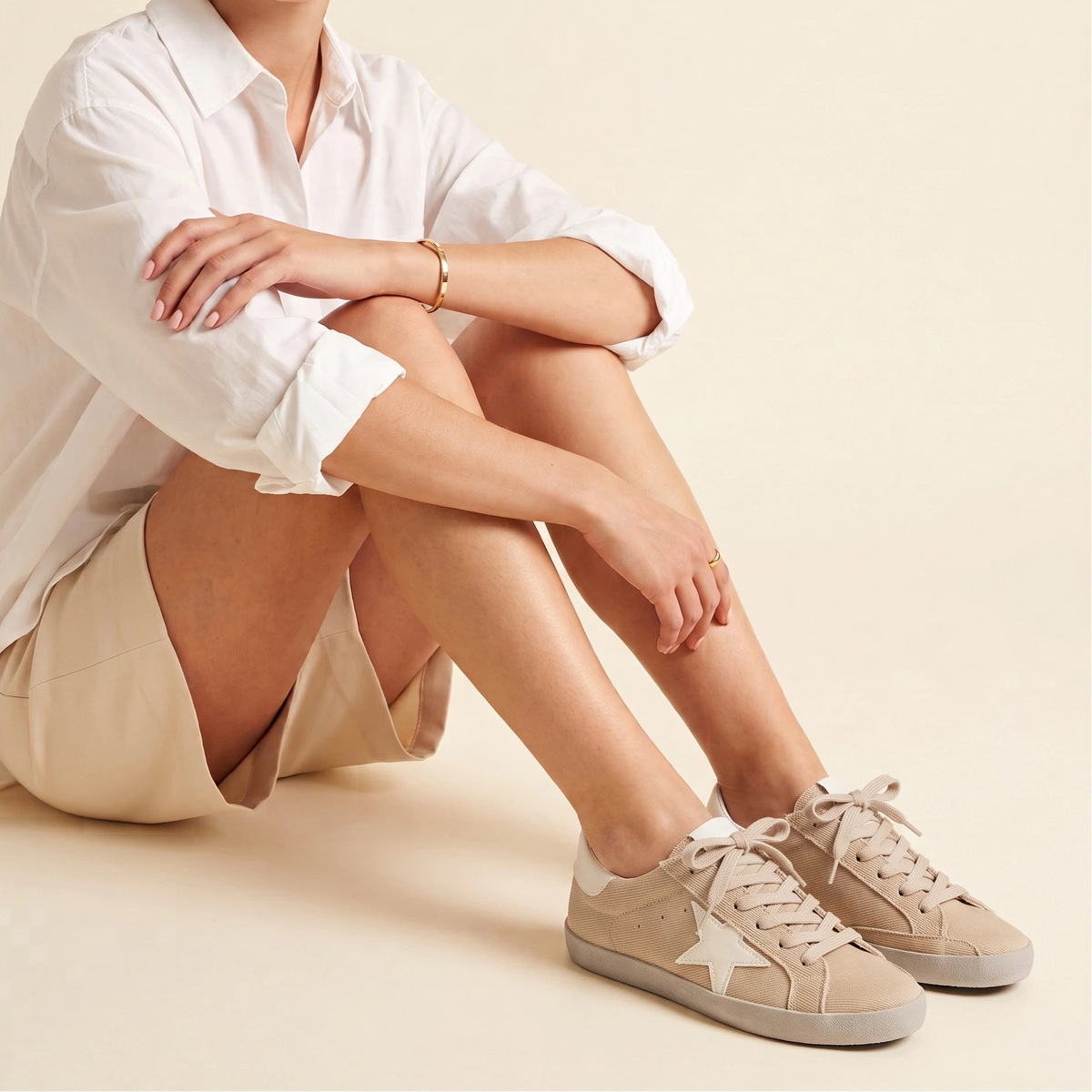 A beige canvas low-top sneaker with a white star logo on the side, beige laces, and a light beige sole