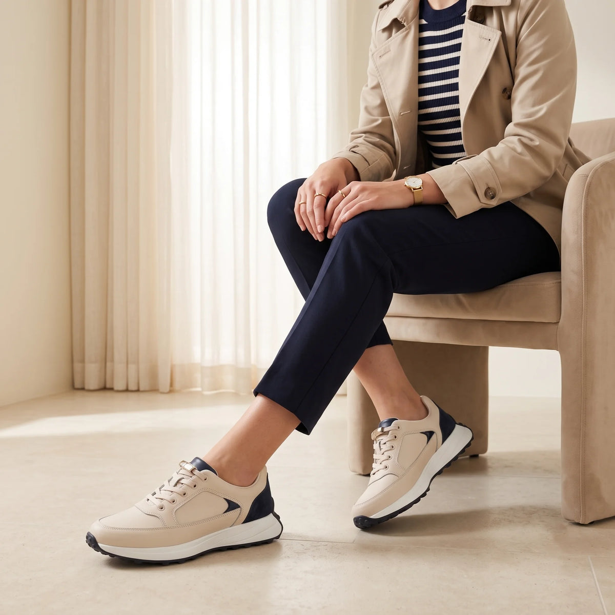 A low-top sneaker in light beige leather with a dark navy heel panel and a thick white midsole