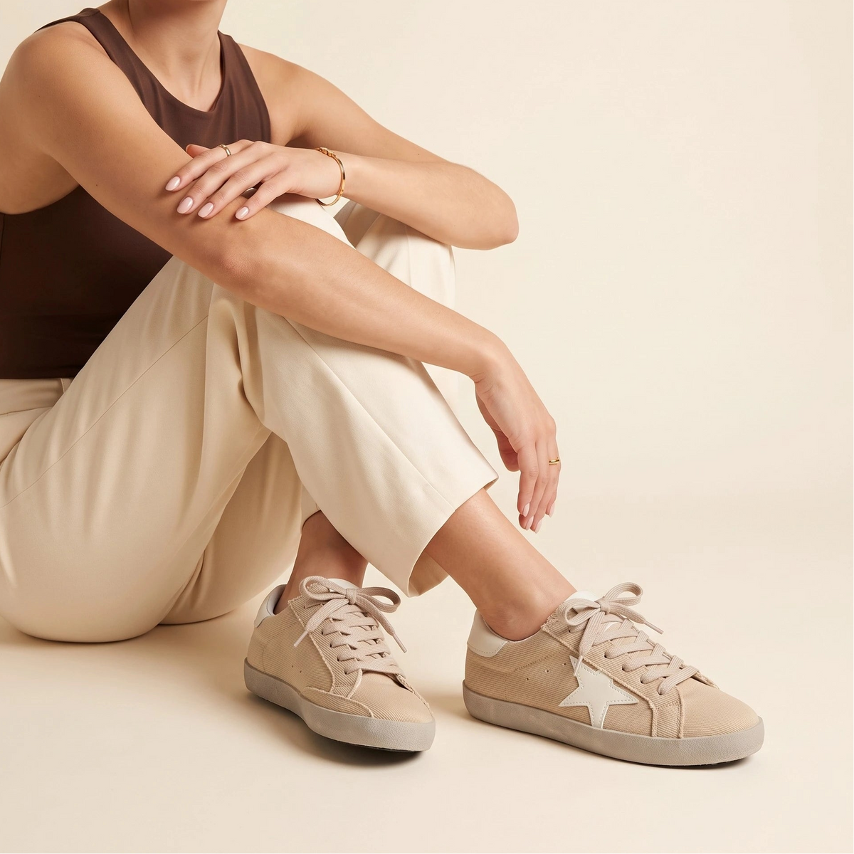 A beige canvas low-top sneaker with a white star logo on the side, beige laces, and a light beige sole