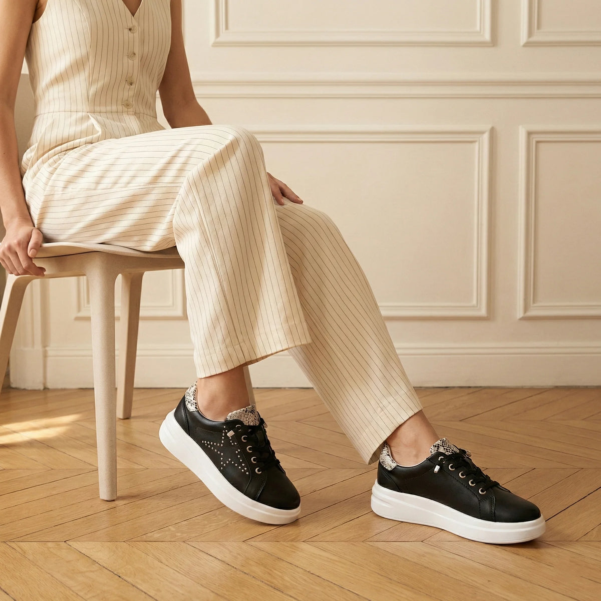 A black low-top platform sneaker with silver stud embellishments, a white platform sole, and a snakeskin-patterned heel tab