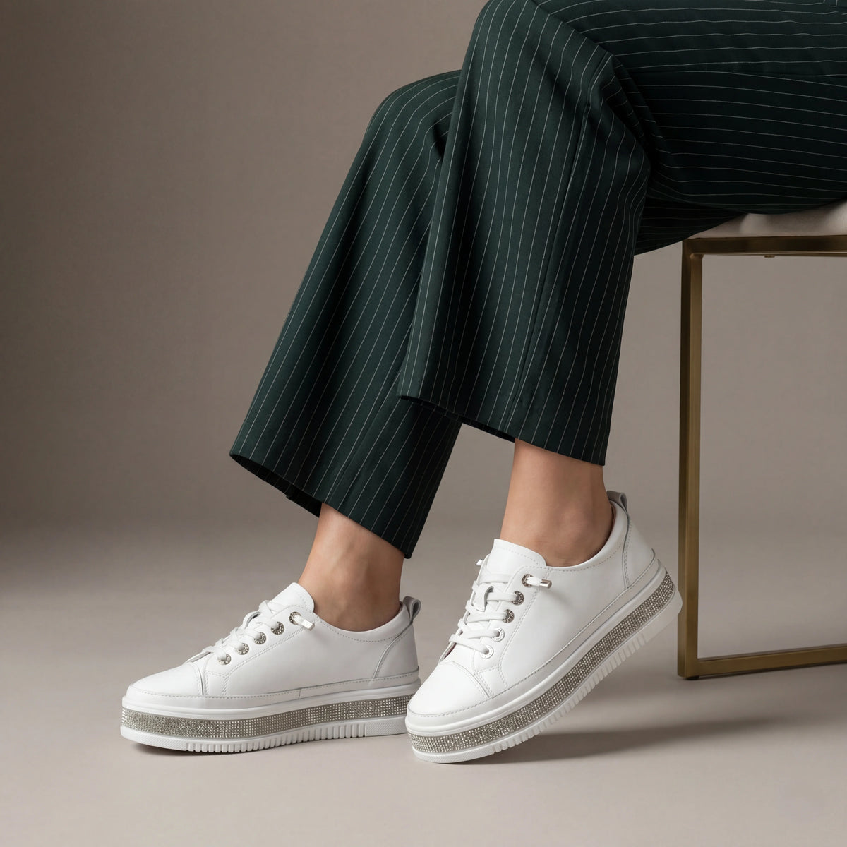 A white low-top platform sneaker with a textured, rhinestone-embellished midsole and white laces